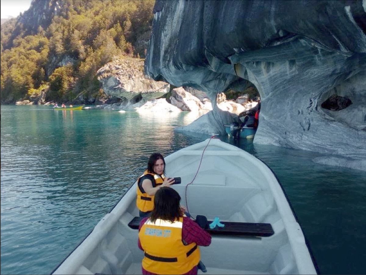 Lancha entrando a una caverna de mármol de aguas turquesa